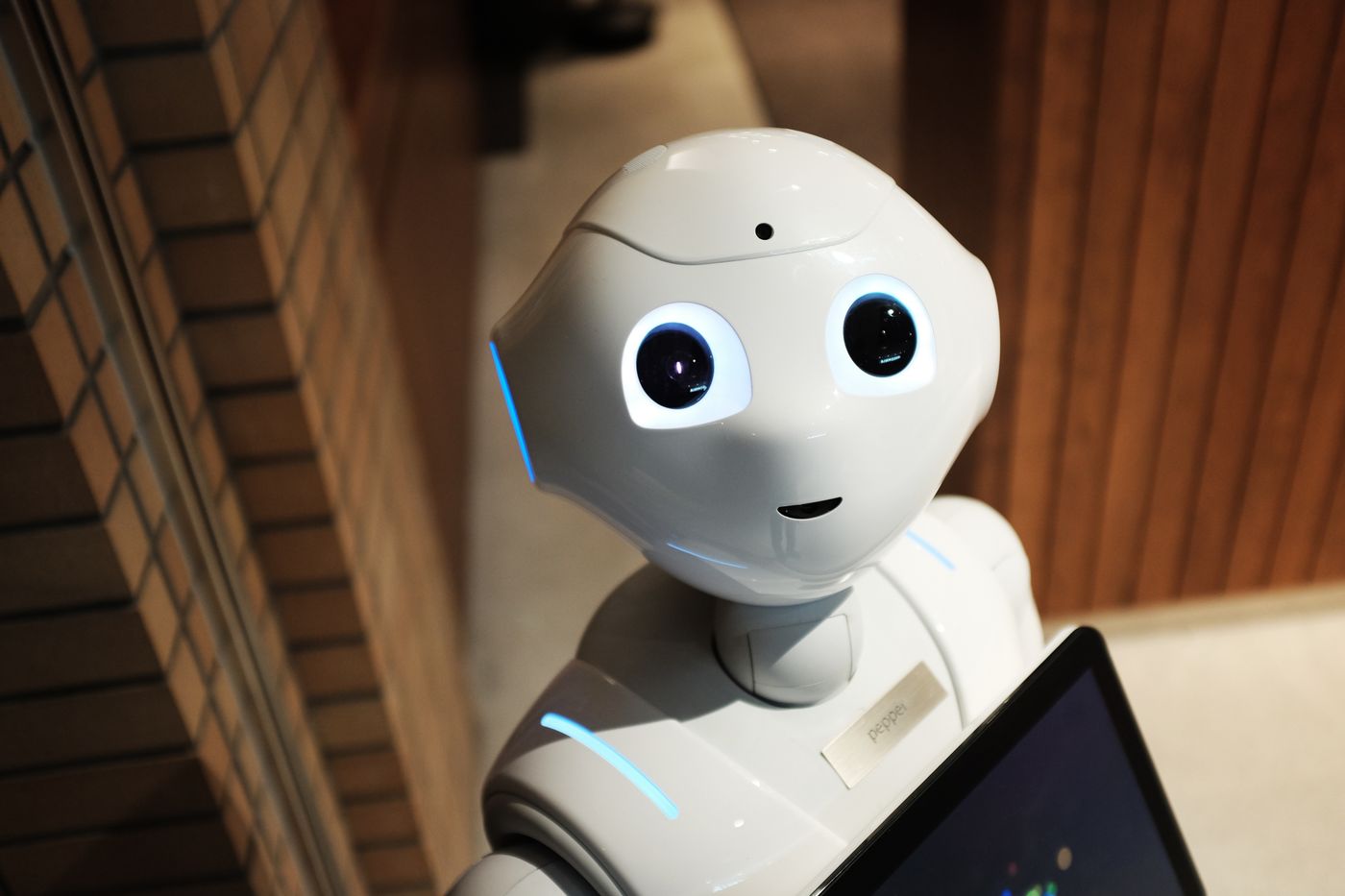 Robot trợ lý màu trắng với đôi mắt tròn đang cầm máy tính bảng