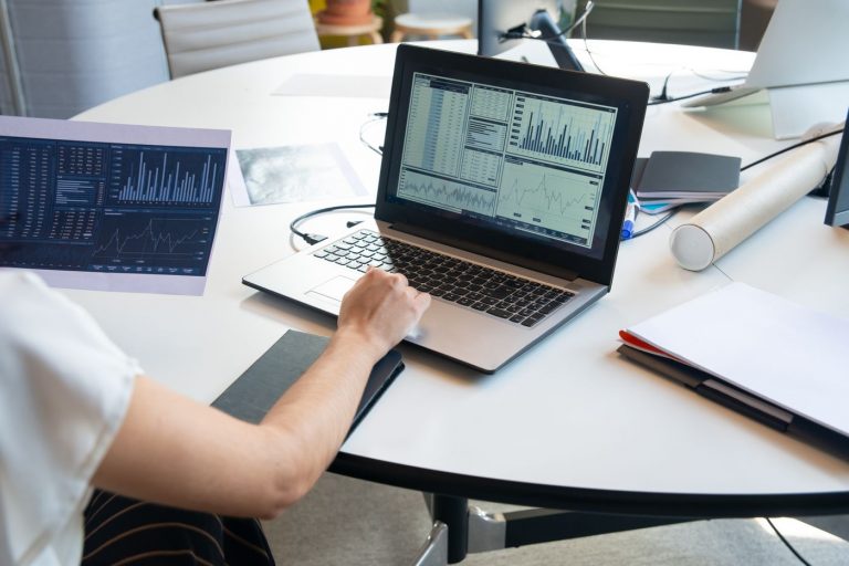 Người xem biểu đồ tài chính trên laptop và giấy báo cáo