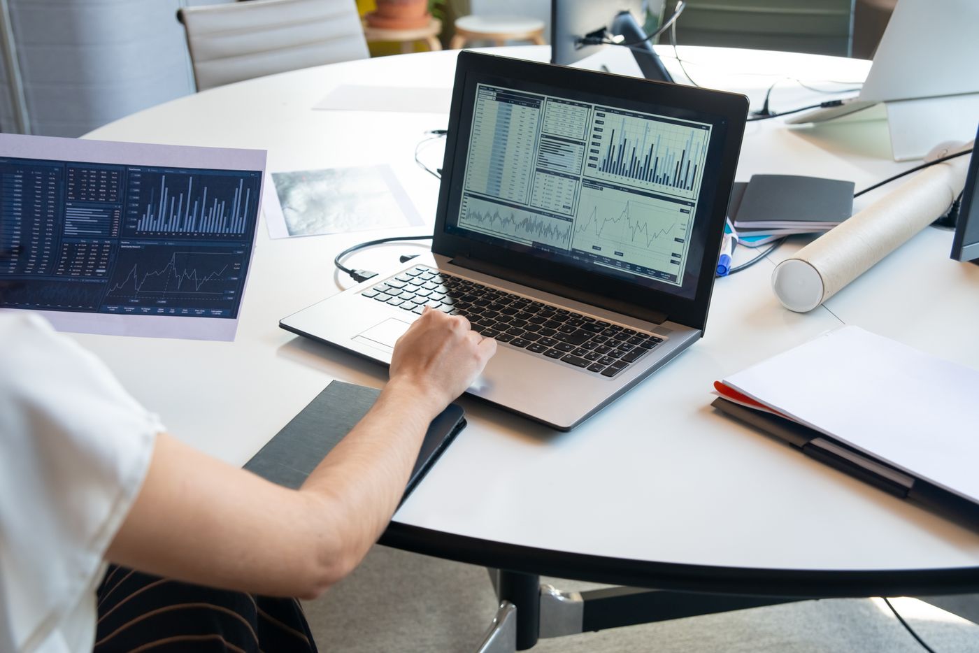 Người xem biểu đồ tài chính trên laptop và giấy báo cáo