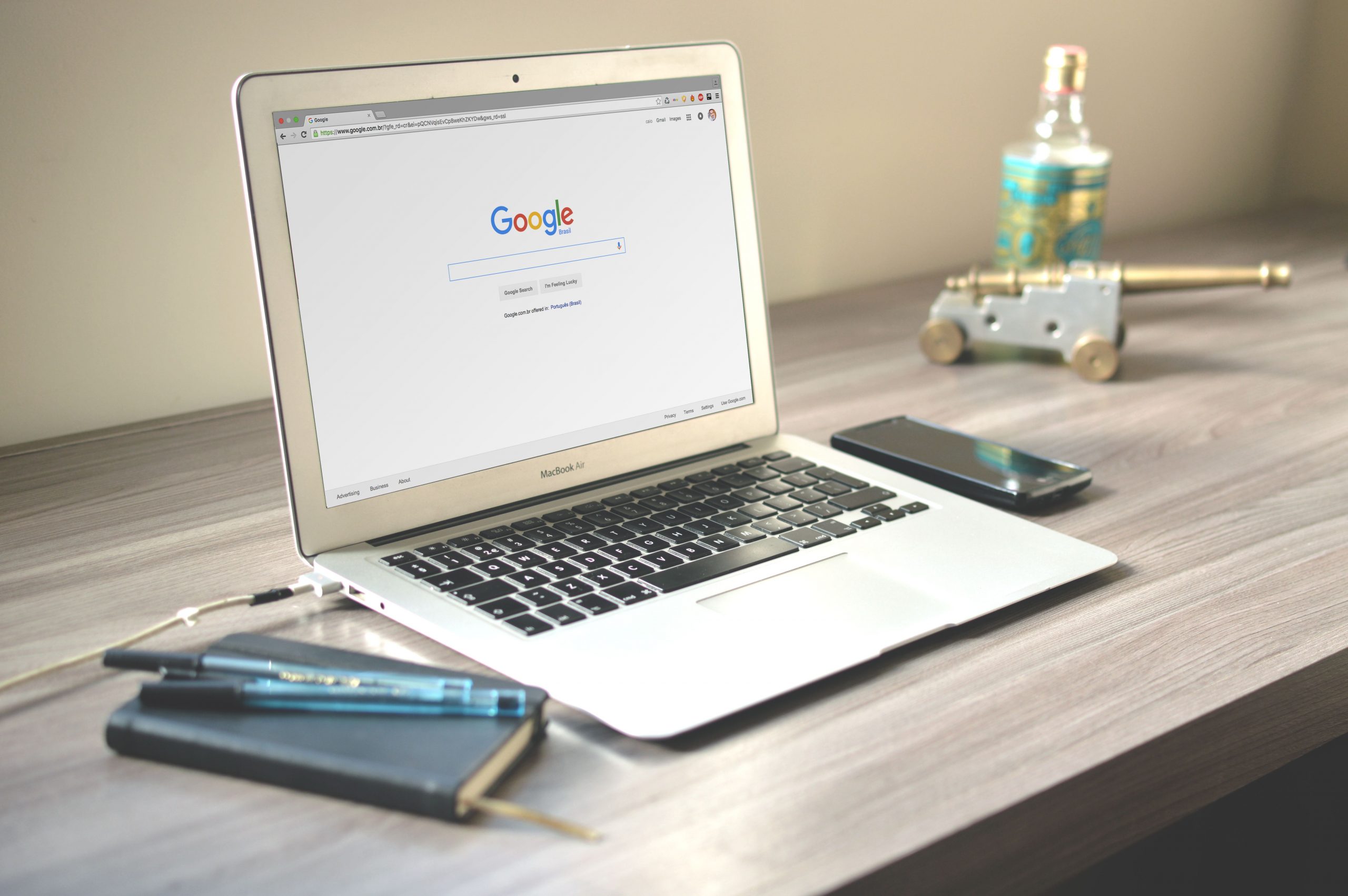 Bàn làm việc gỗ có laptop mở trang tìm kiếm, điện thoại và sổ tay